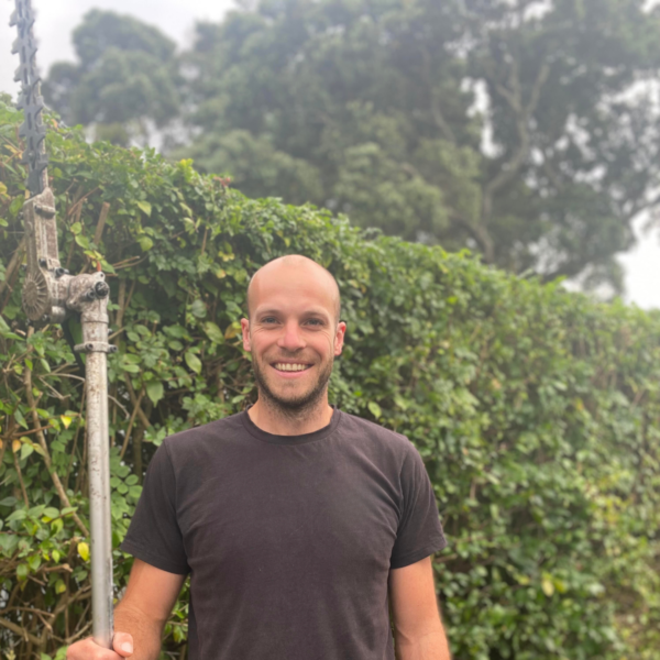 man standing in front of hedge holding a hedge trimmer