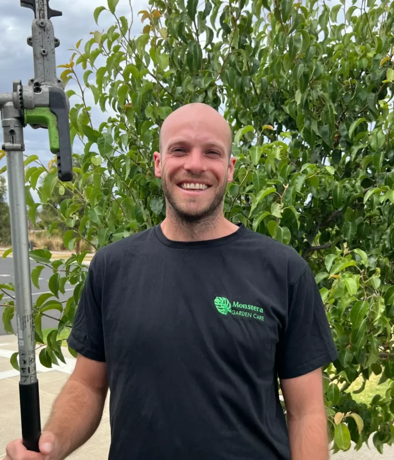 Matt Monstera Garden Care holding hedge trimmer in front of tree